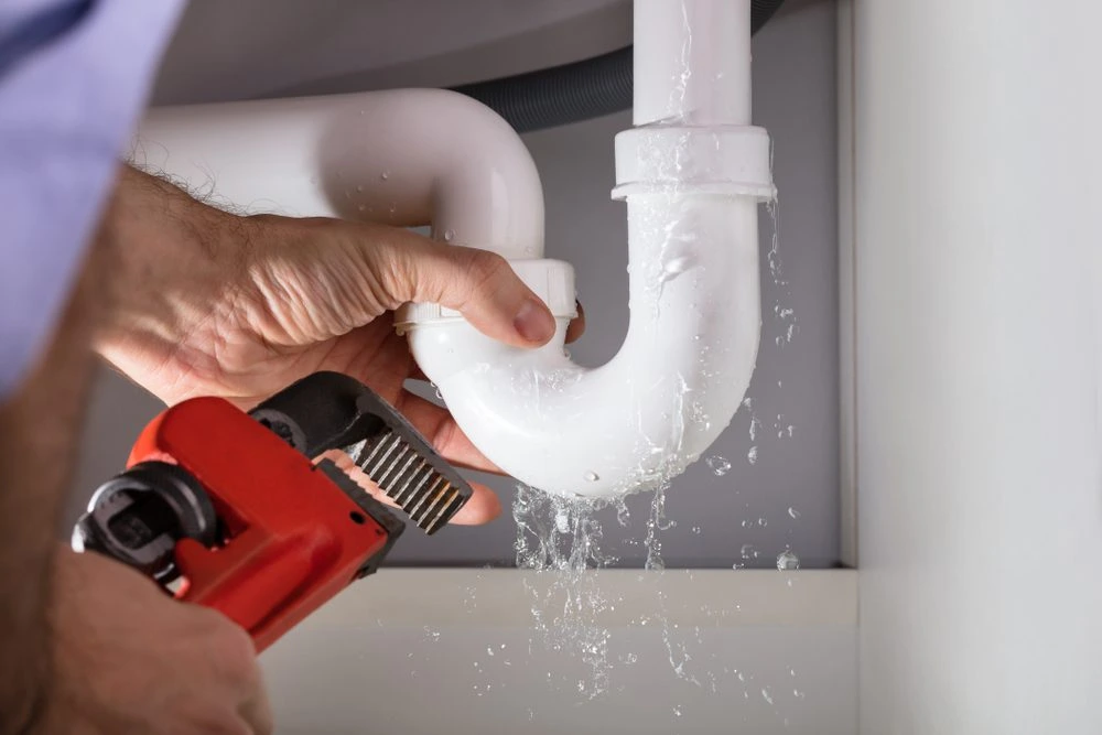 Close-up of a leaking P-trap under a bathroom sink requiring an emergency plumber for immediate repair