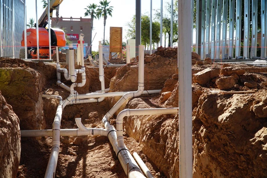 Large-scale commercial plumbing installation featuring a complex network of underground PVC drainage and waste lines for a new construction project